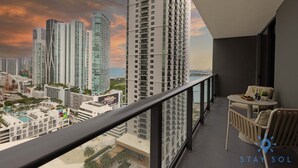 Un balcon avec vue sur des immeubles de grande hauteur et sur une étendue d’eau.
