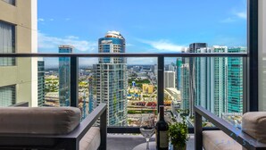 A high-rise balcony with a city view, including modern buildings and a clear sky.
