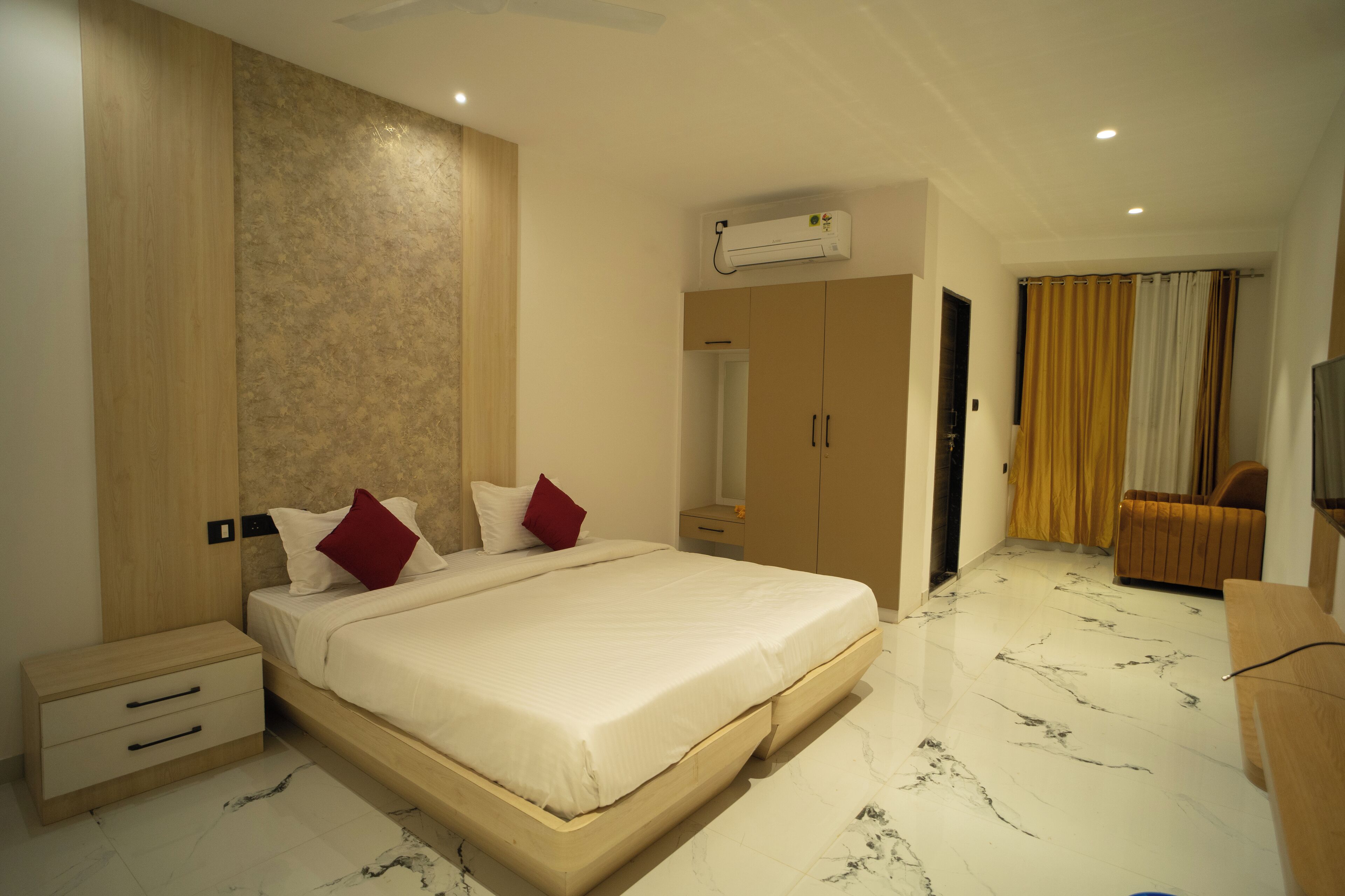 A modern bedroom with a large bed, wooden wardrobe, and a seating area.