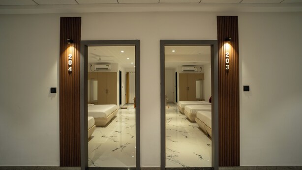A hotel room with a mirrored wall, a marble floor, and a bed with a headboard.