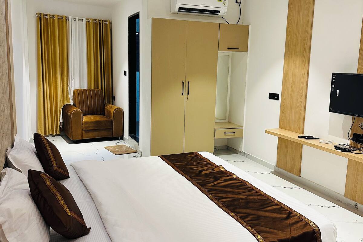 Een hotelkamer met een bed, een stoel, een kledingkast, een bureau en een televisie.