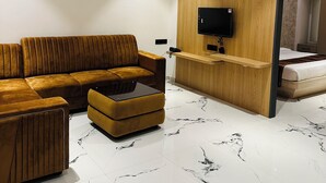 A modern living room with a sectional sofa, a coffee table, and a TV mounted on a wooden wall.