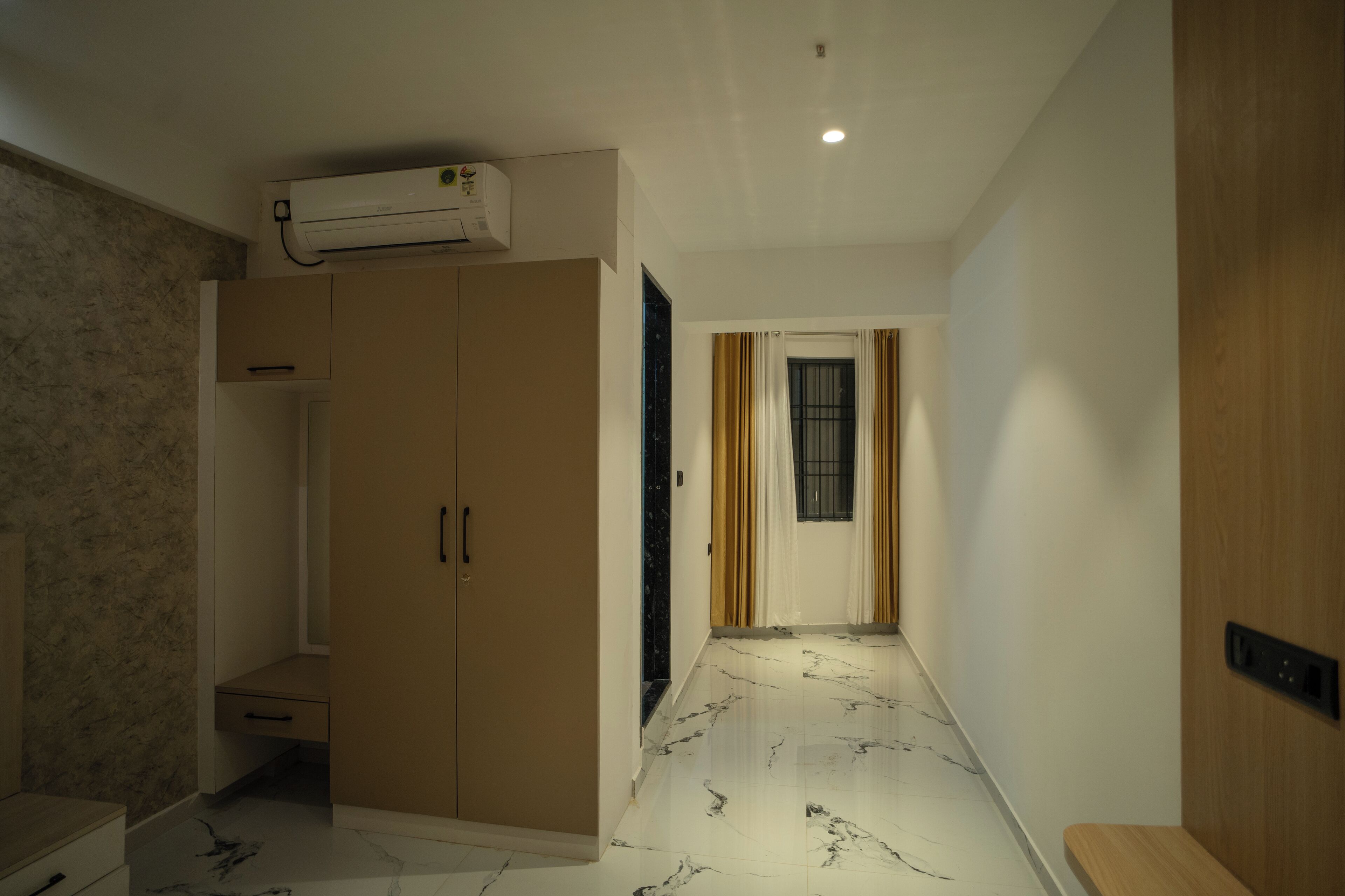 A hallway with a wardrobe, a marble floor, and a ceiling-mounted air conditioner.