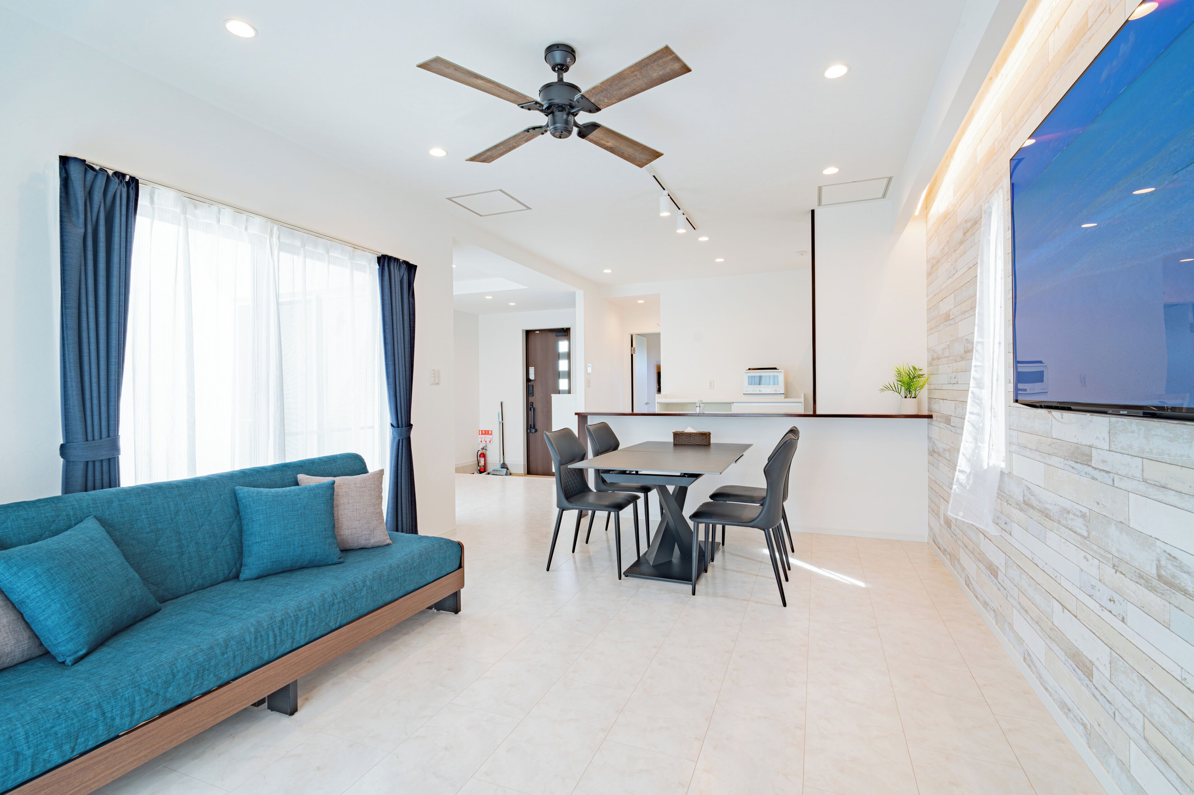 A modern living room with a sofa, dining table, chairs, and a ceiling fan.