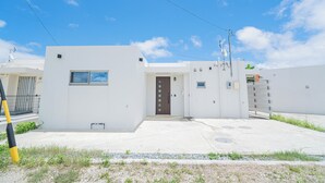 A modern building with a brown door, a window, and a small sign. - Porte Bonheur (Miyakojima)