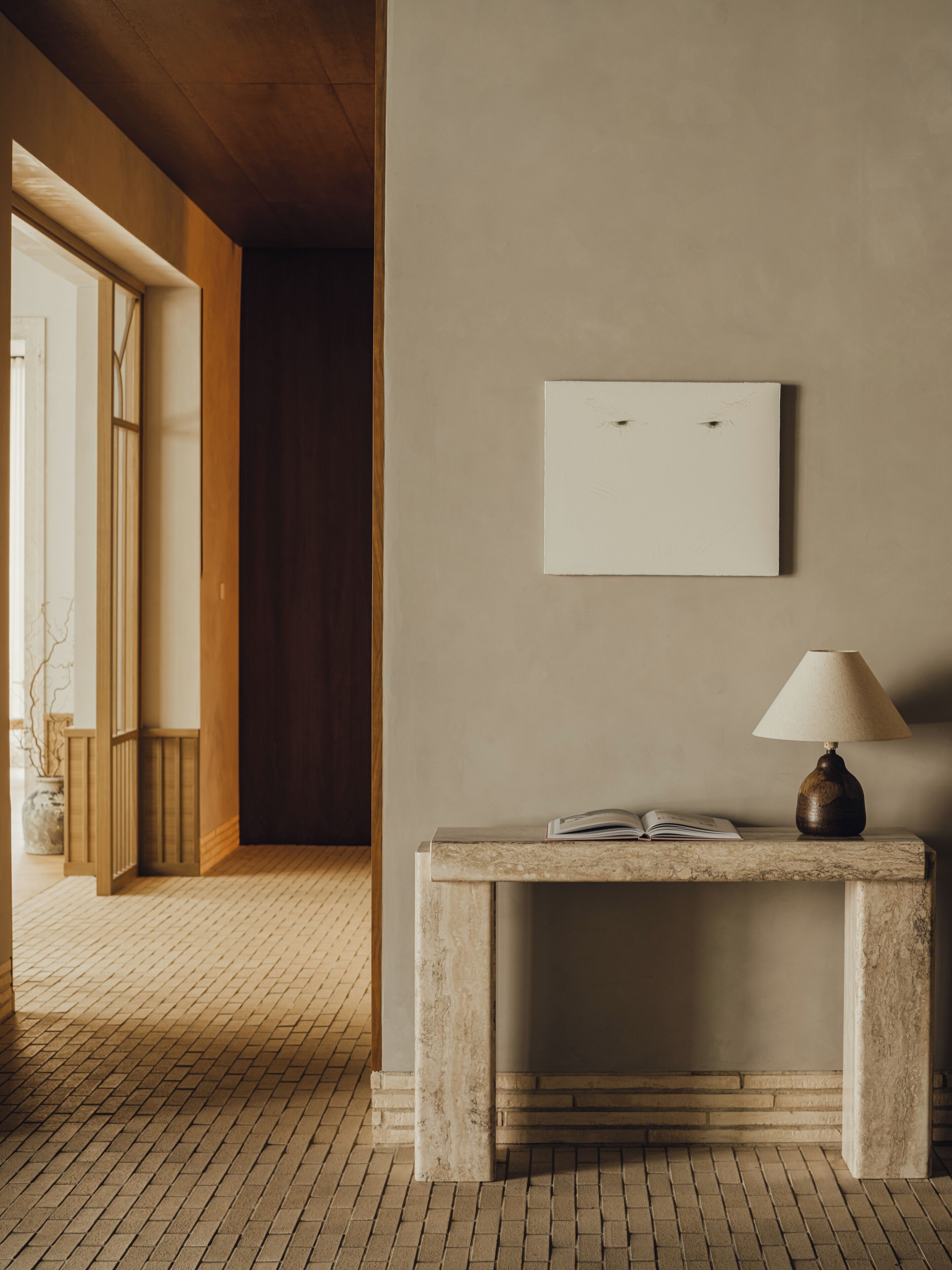 A room with a marble console table, a lamp, and a framed picture on the wall.