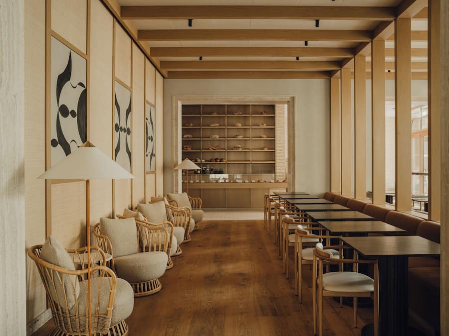 A restaurant with wooden floors, wicker chairs, and tables.