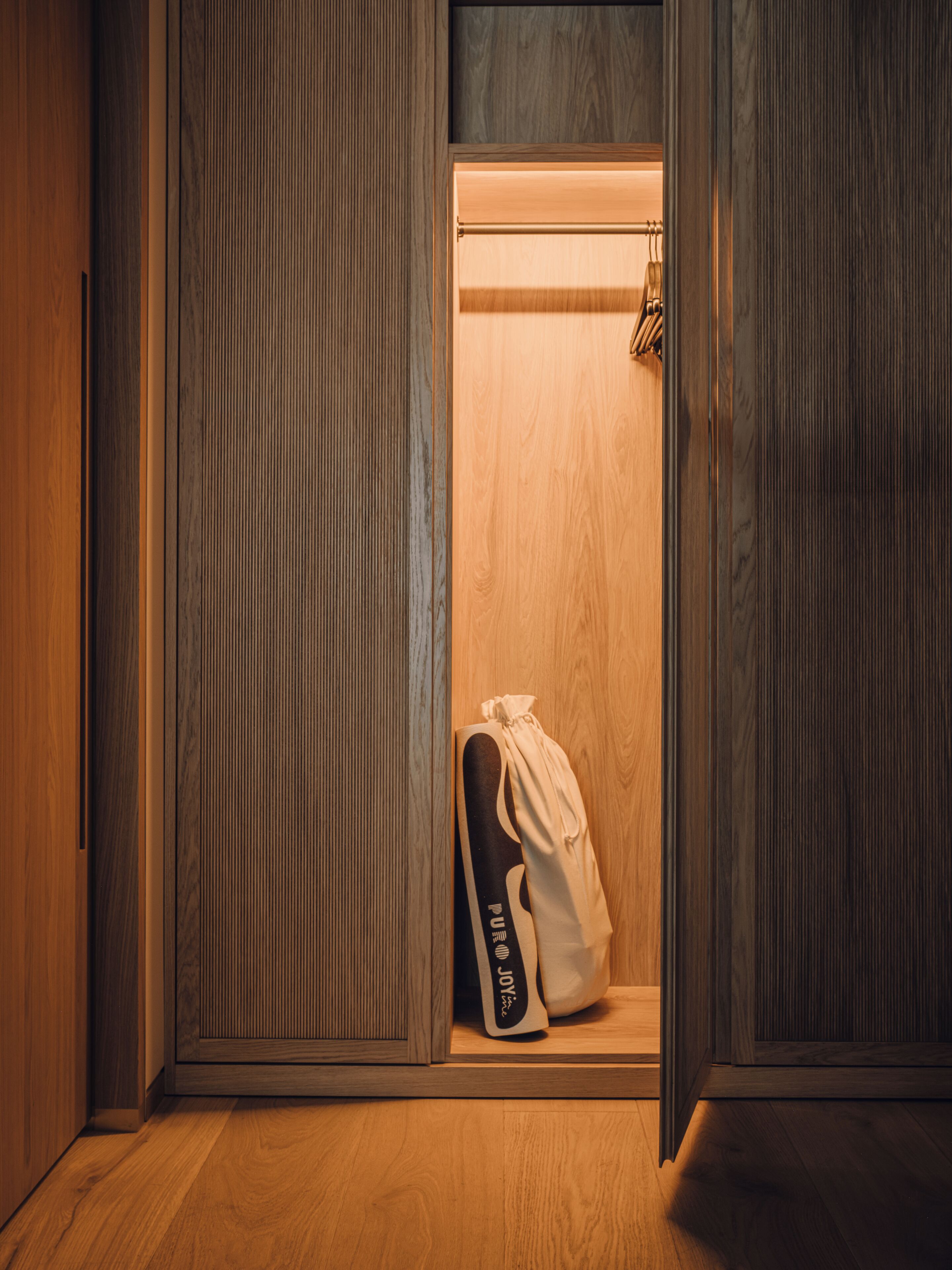 A wooden wardrobe with a hanging shoe rack inside.