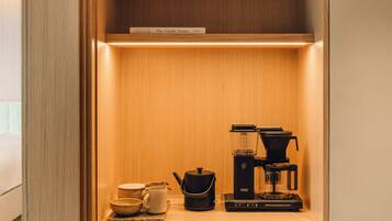 A wooden cabinet with a coffee maker, a kettle, and a book titled "The Nordic Home".