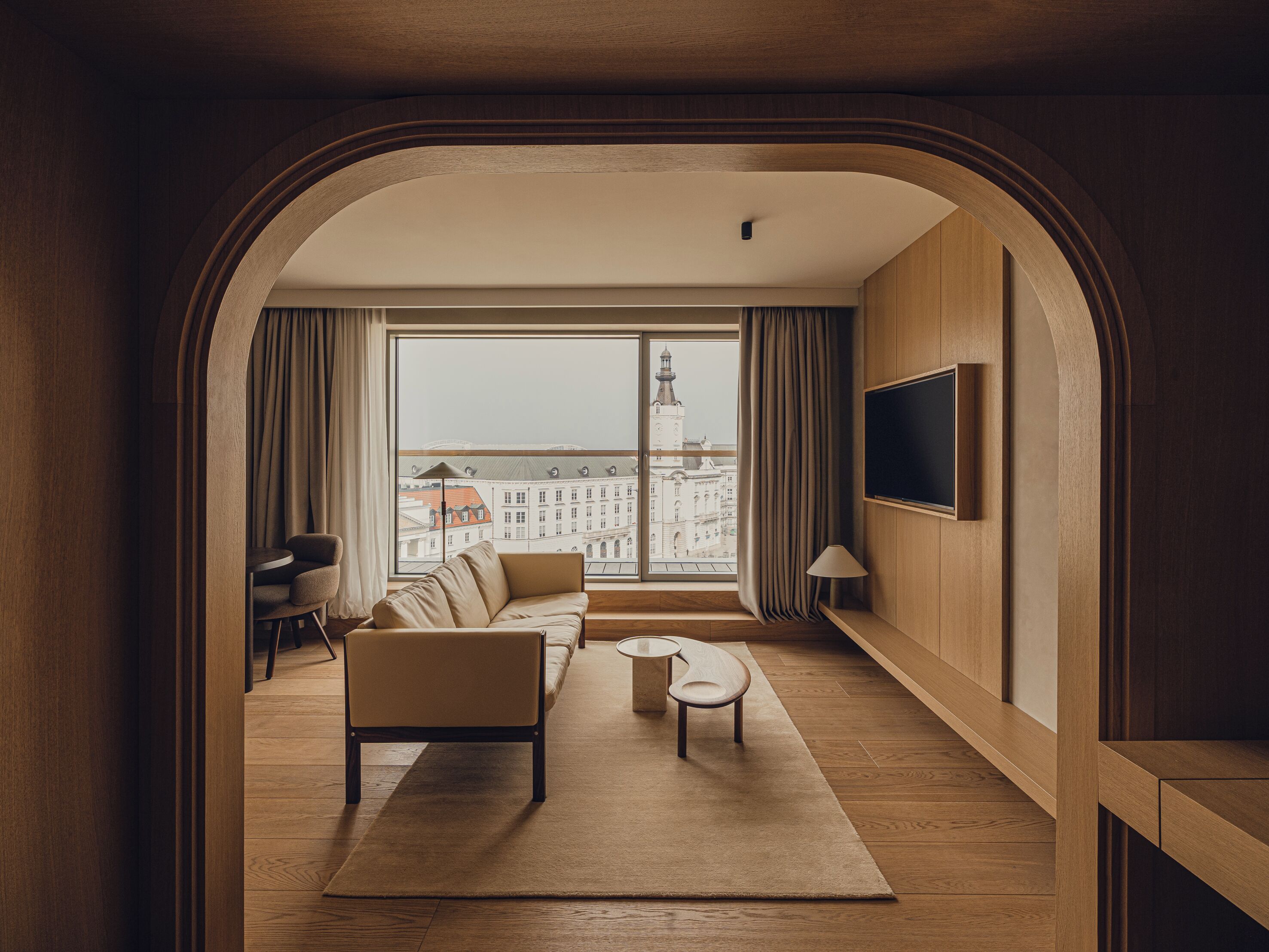 A modern living room with a sofa, a coffee table, and a TV mounted on the wall.
