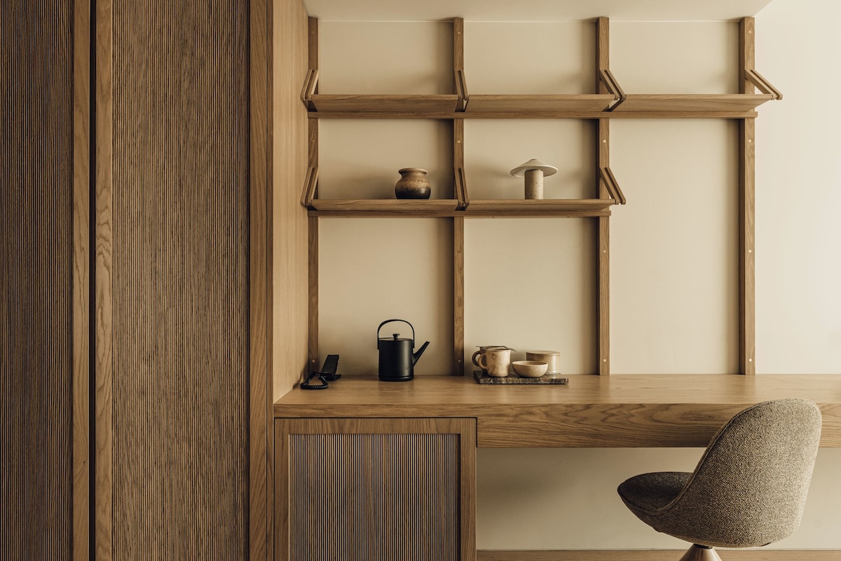 Un escritorio de madera con estantes, una silla y una tetera.