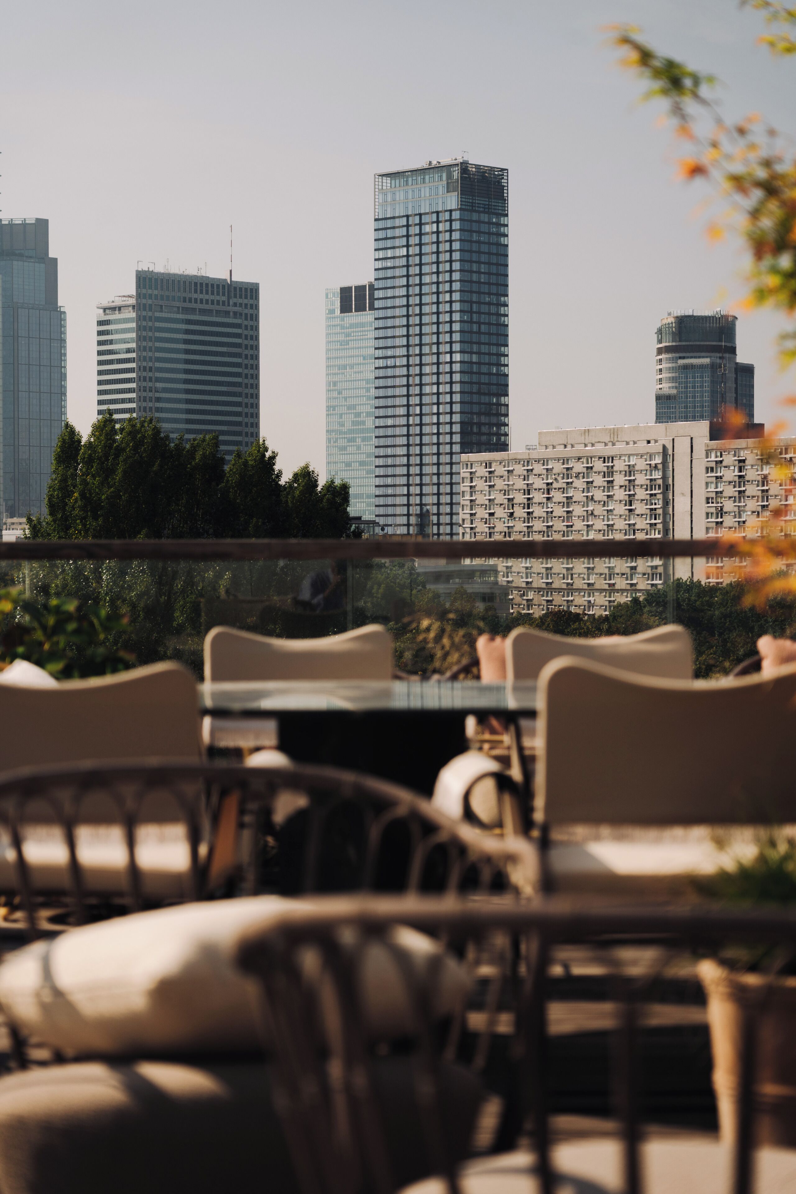 Una terraza en la azotea con vistas a modernos rascacielos, mobiliario exterior y cielo despejado.