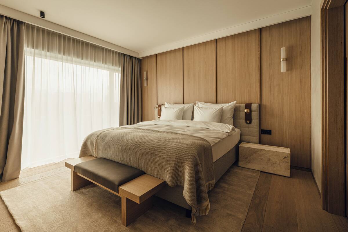 Ein modernes Schlafzimmer mit einem großen Bett, einer Bank und einem Holzkopfende.