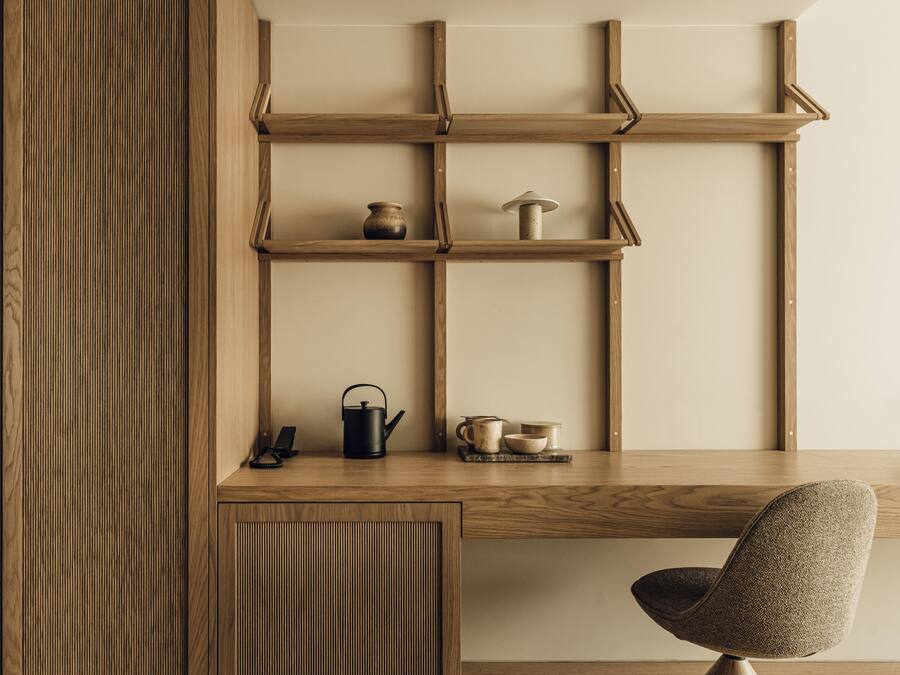 A wooden desk with shelves, a chair, and various kitchen items.