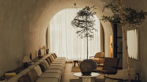 Un salon chaleureux avec un canapé, des fauteuils, une table basse et un grand arbre.