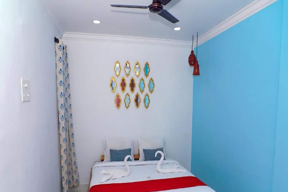 A room with a bed, a ceiling fan, a wall with decorative items, and a curtain.