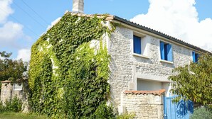 A stone building with a chimney, ivy-covered walls, and a blue door. - Safari tent with all comforts, garden, swimming pool, between La Rochelle and Venise verte (Le Gué-d'Alleré)