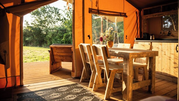 A wooden table and chairs inside a tent with a view of the outdoors. - Safari tent with all comforts, garden, swimming pool, between La Rochelle and Venise verte (Le Gué-d'Alleré)