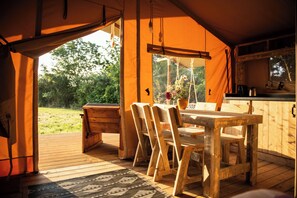 A wooden table and chairs inside a tent with a view of the outdoors. - Safari tent with all comforts, garden, swimming pool, between La Rochelle and Venise verte (Le Gué-d'Alleré)