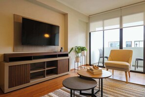 Relax in this stylish living room with a large flat-screen TV, entertainment unit, and comfortable armchair.