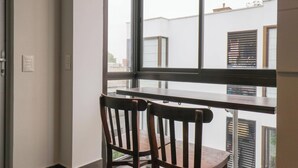 Une pièce avec une grande fenêtre, deux chaises en bois et une petite table.