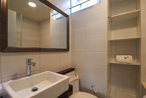 Bathroom features a large sink and mirror, with a convenient shelf for storing essentials.