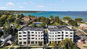 Ein moderner Wohnkomplex mit mehreren Etagen, einem Parkplatz und Blick aufs Meer.
