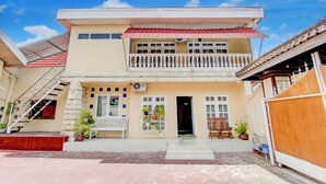 Una casa a due piani con un balcone, una scala e piante in vaso.