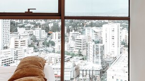Ein geräumiges Zimmer mit großen Fenstern und Blick auf die Stadt.