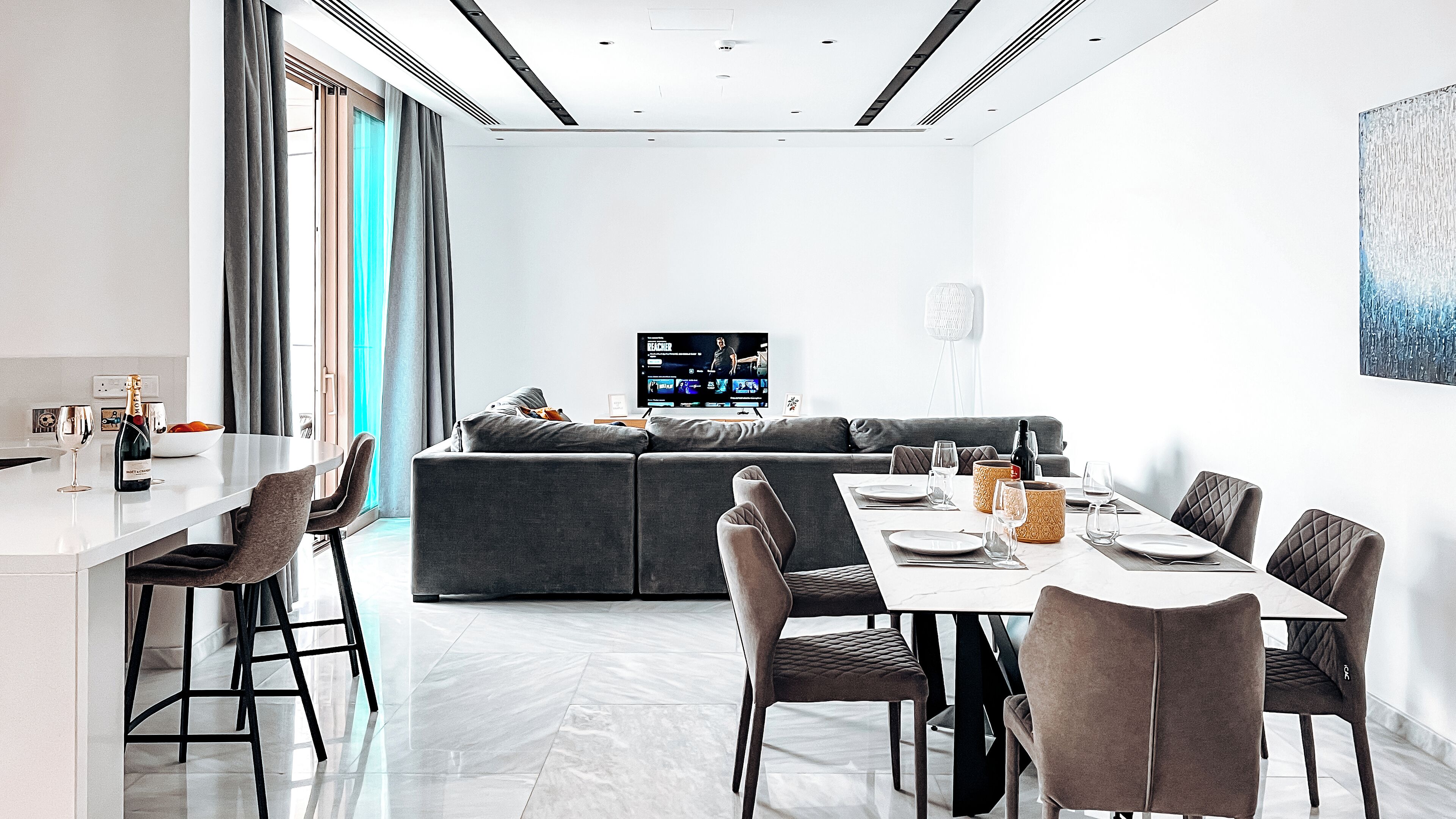 Una sala de estar moderna con comedor, un televisor de pantalla plana grande y un diseño minimalista.