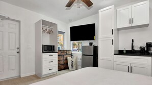 Une chambre moderne avec un grand lit, une armoire, un four à micro-ondes encastré et un réfrigérateur.
