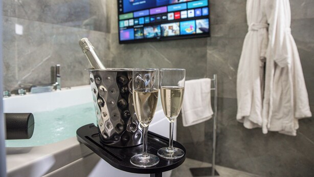 A bathroom with a bathtub, a television mounted on the wall, and a towel rack with a white towel. - Karma6Rooms (Catania)