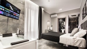 A modern hotel room with a large flat-screen TV, a bed, a bathroom with a mirror, and a marble floor. - Karma6Rooms (Catania)