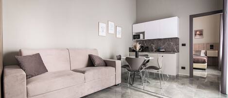 Una sala moderna con un sofá, una mesa de comedor y una zona de cocina.