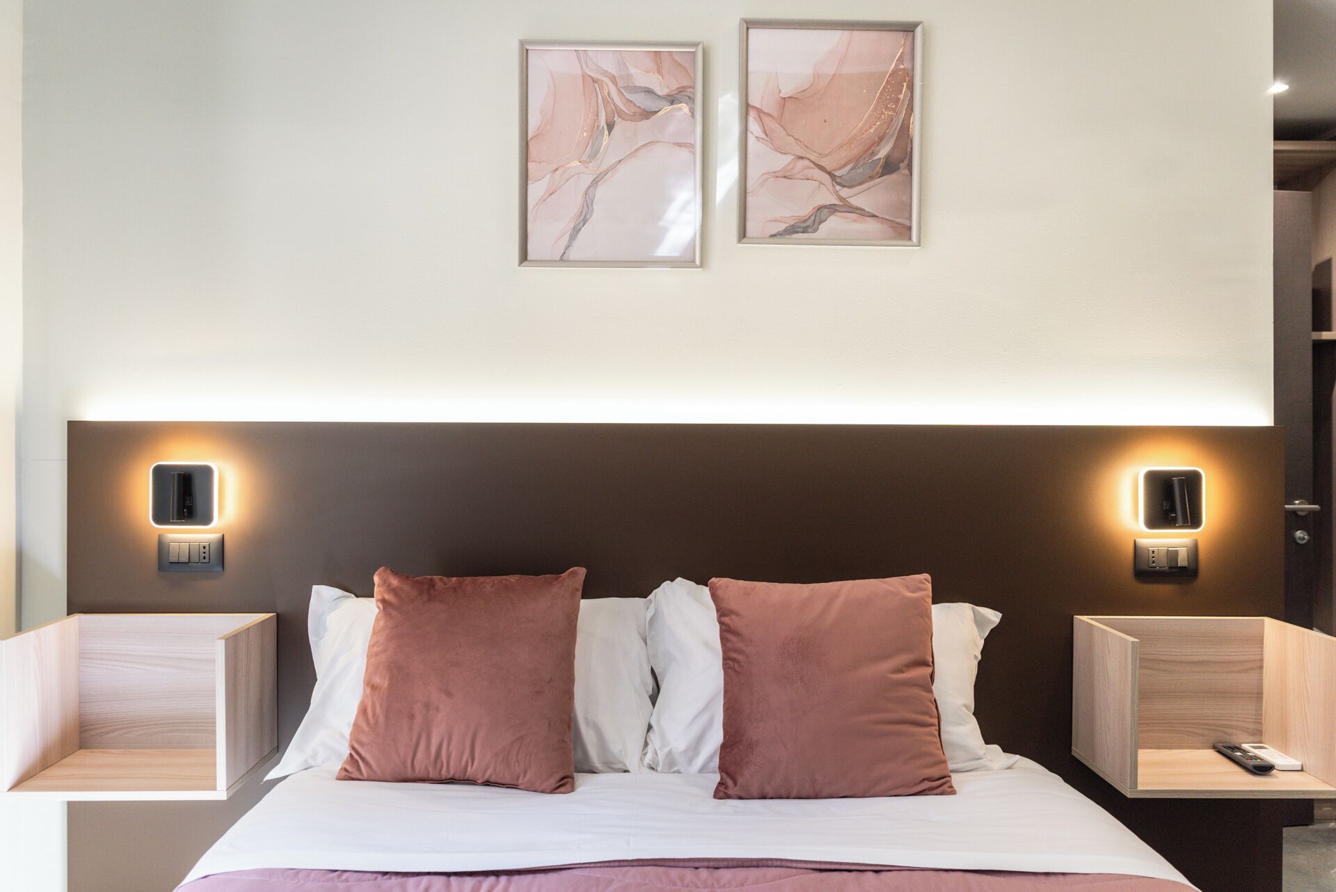 Ein modernes Hotelzimmer mit einem großen Bett, zwei Nachttischen und Wandleuchten.