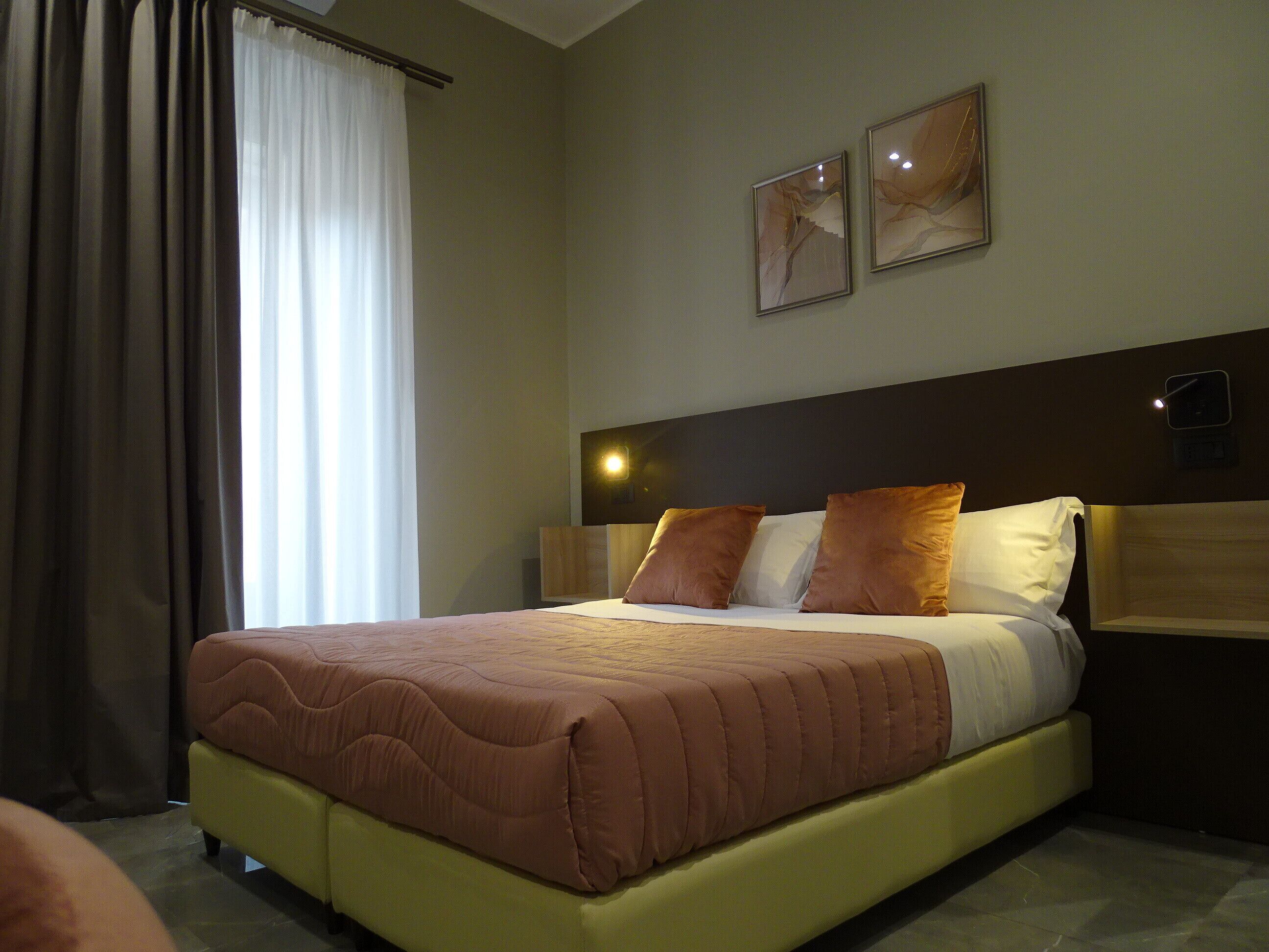 A hotel room with a large bed, a nightstand, and two wall-mounted light fixtures.