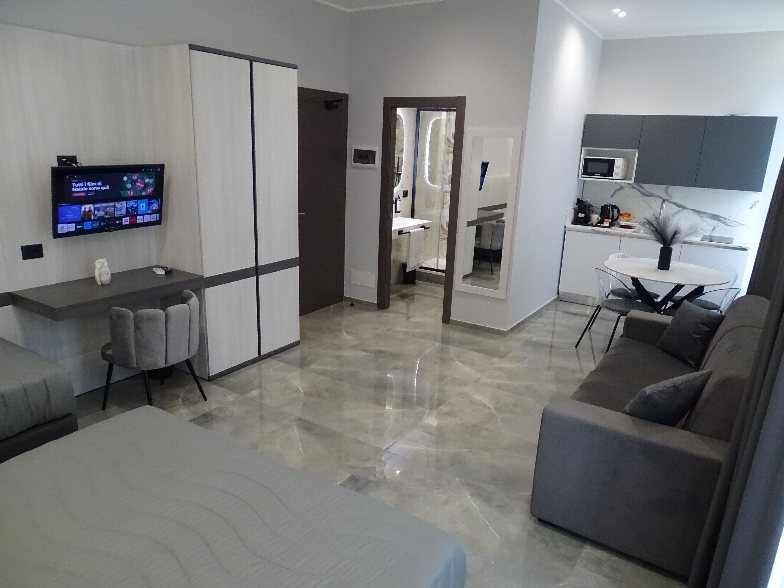 A modern living room with a sofa, a TV, and a kitchen area with a dining table.