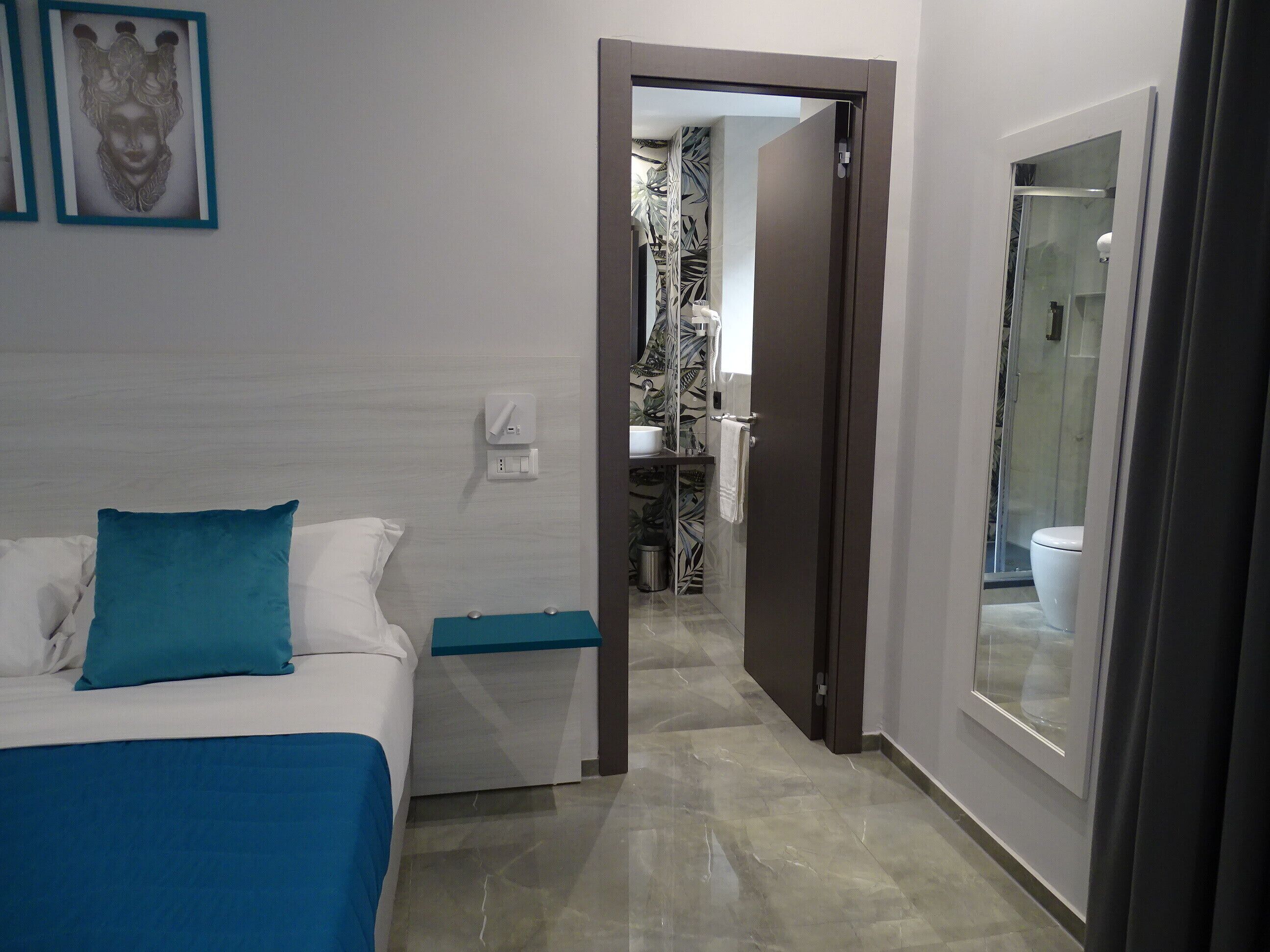 Una habitación de hotel con cama, mesita de noche y baño que incluye inodoro y ducha.