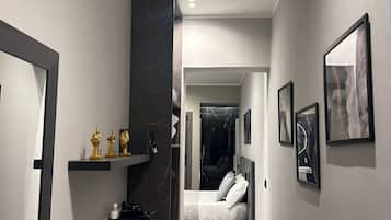 Una camera d'albergo moderna con un letto, un comodino e un bagno dotato di specchio e lavabo.