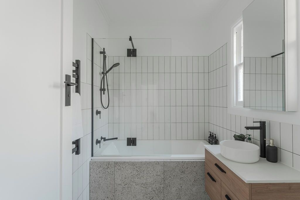 A modern bathroom with a freestanding bathtub, a large mirror, and a wooden vanity with a sink.