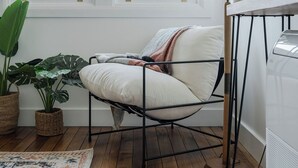 A modern room with a metal-framed chair, a large potted plant, and a wooden floor. - Burnie Retreat - Coastal Comfort Awaits (Burnie)