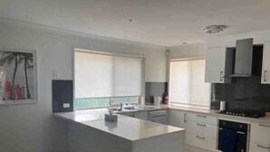 Une cuisine moderne dotée d’un îlot central, de meubles blancs et d’une grande fenêtre qui laisse entrer la lumière naturelle.