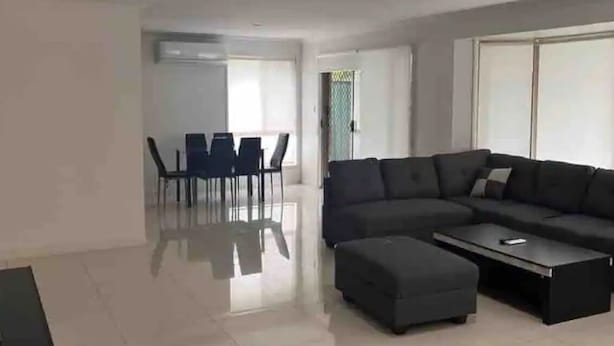 Un salon moderne comprenant un canapé d’angle, une table basse et un coin repas avec des chaises et une table.