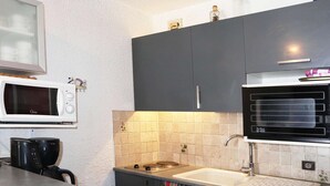 A compact kitchen with a microwave, coffee maker, and a sink.