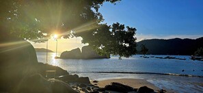 A beach with a clear view of the water, rocks, and a boat in the distance. - The Coral Homestay & Pub (Da Nang)