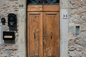 A wooden double door with a number 33 sign above it, set in a stone wall. - Old village house (Poggibonsi)