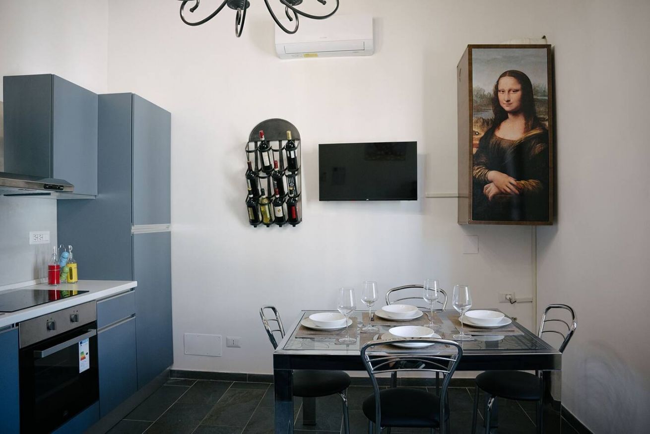 A modern kitchen with a dining area, a wine rack, and a painting of the Mona Lisa.