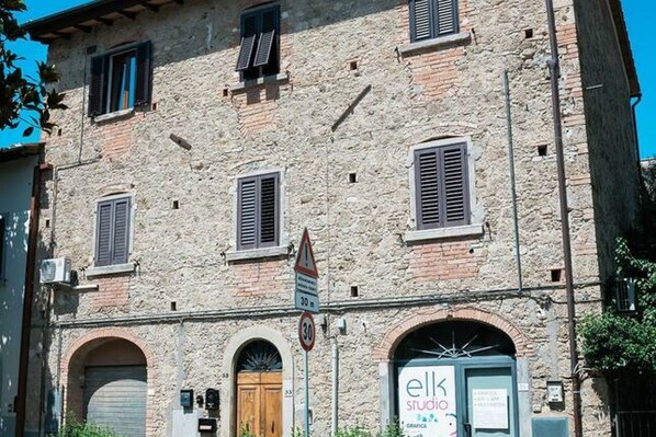 A stone building with arched doorways and shutters, a sign for 'elk studio' with a graphic design, and a speed limit sign of 30 km/h.