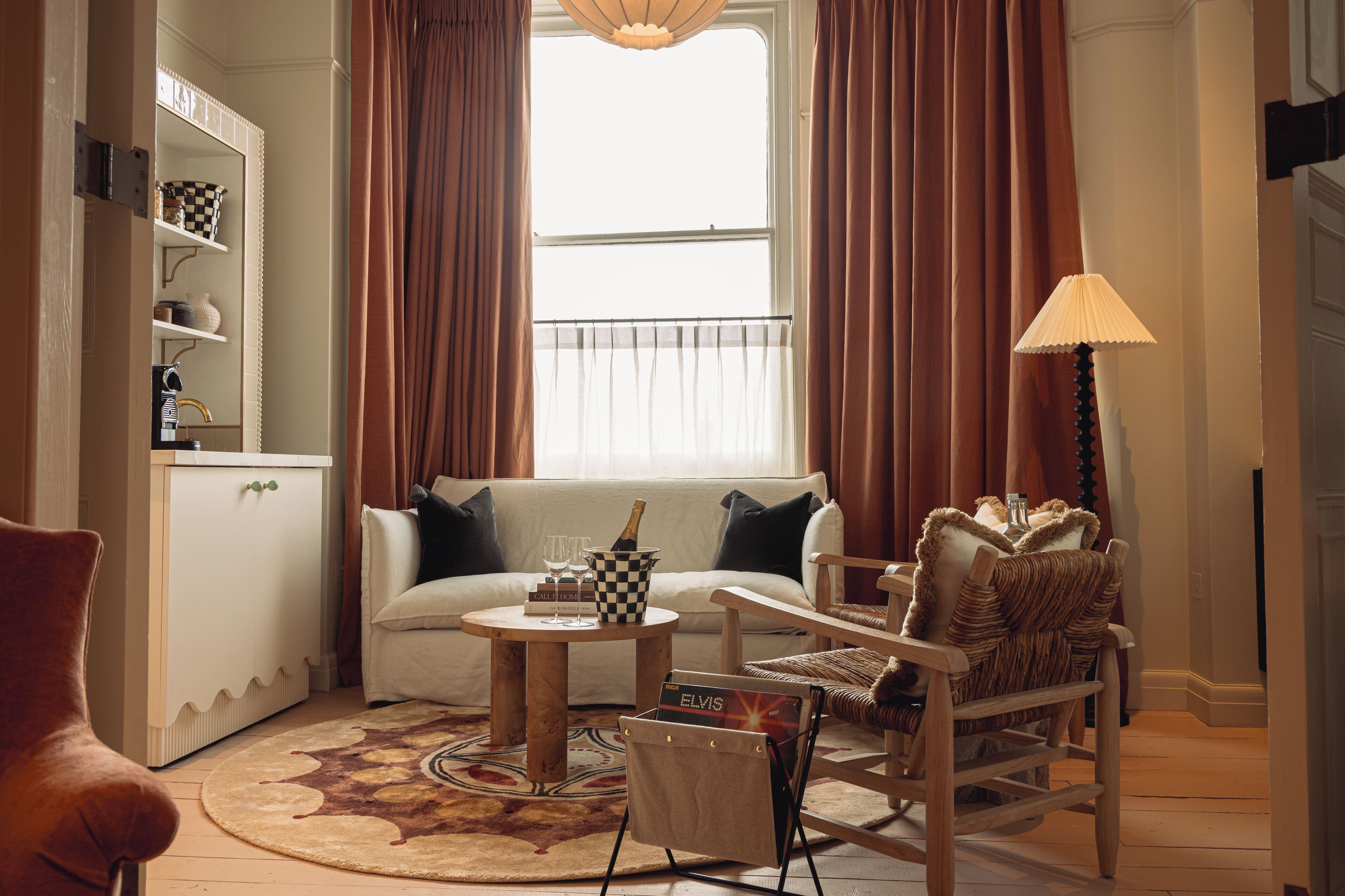 A living room with a sofa, armchairs, a coffee table, a lamp, and a bookshelf.