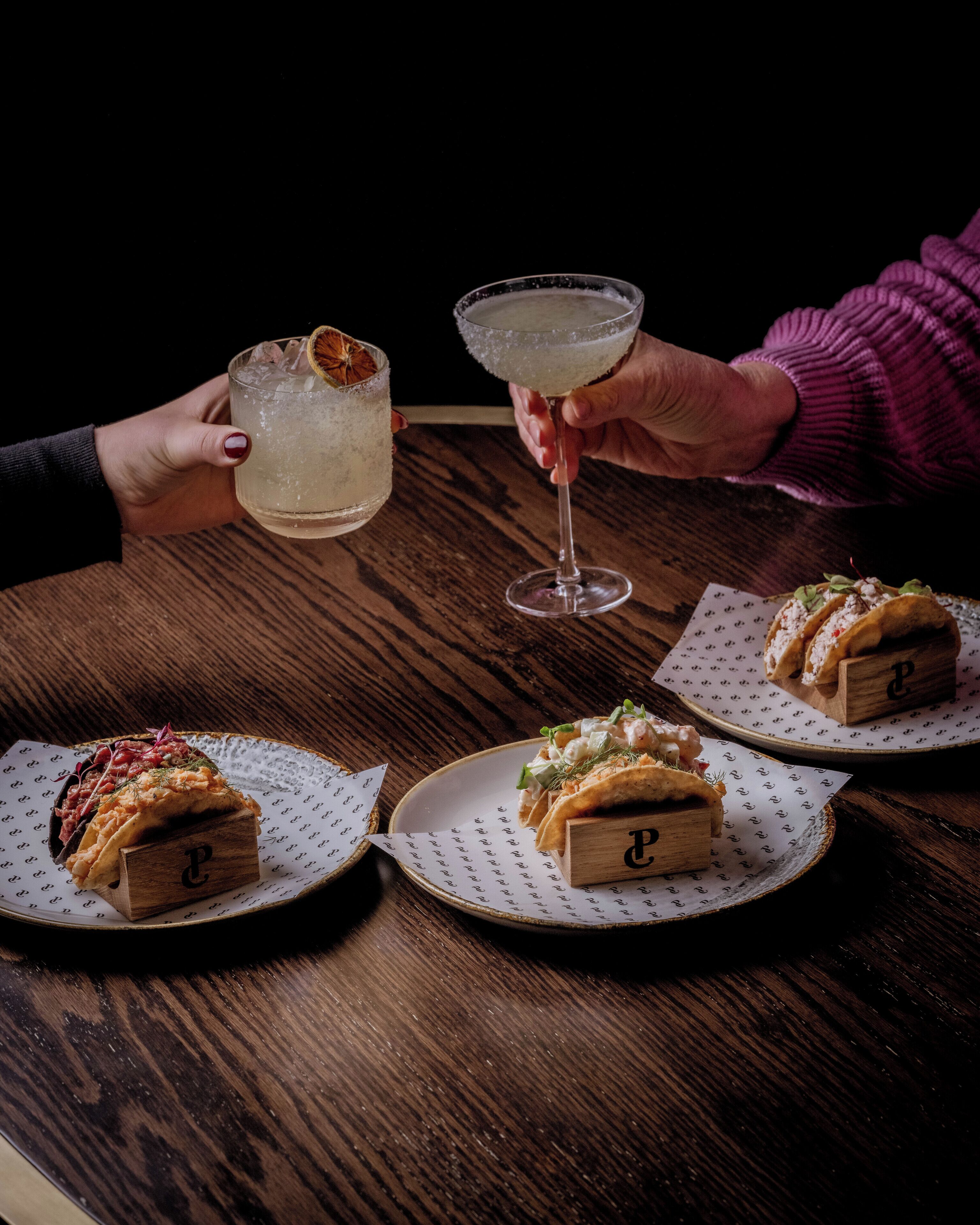A wooden table with two plates of food and two drinks.